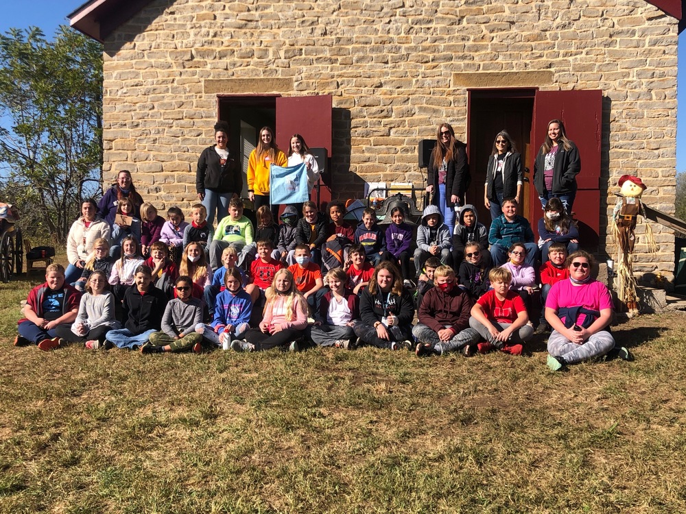 5th Graders sitting in front of an old stone building
